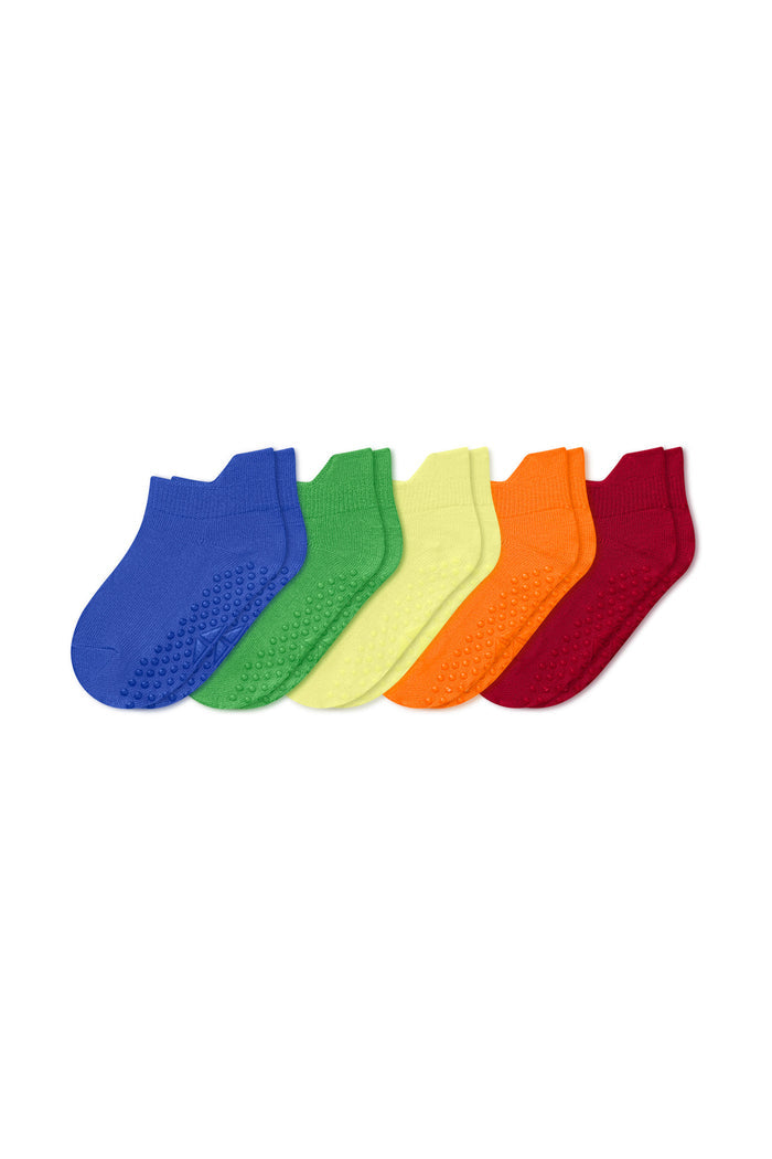 Six pairs of low-cut grip socks arranged in a fan shape, showing a rainbow color sequence of blue, green, yellow, orange, and red on a plain white background.