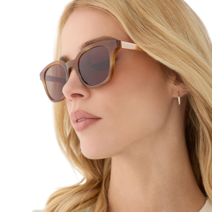 on model - female wearing diff eyewear featuring the bridget round sunglasses with a tawny tortoise frame and brown lenses angled view