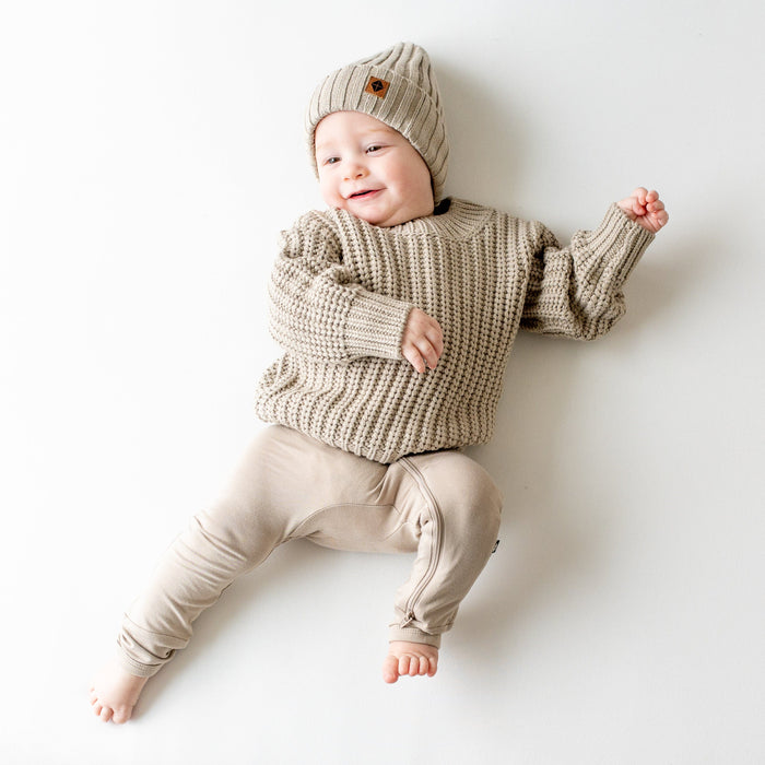 Infant wearing soft and stretch Kyte Baby Chunky Knit Ribbed Beanie in Almond neutral
