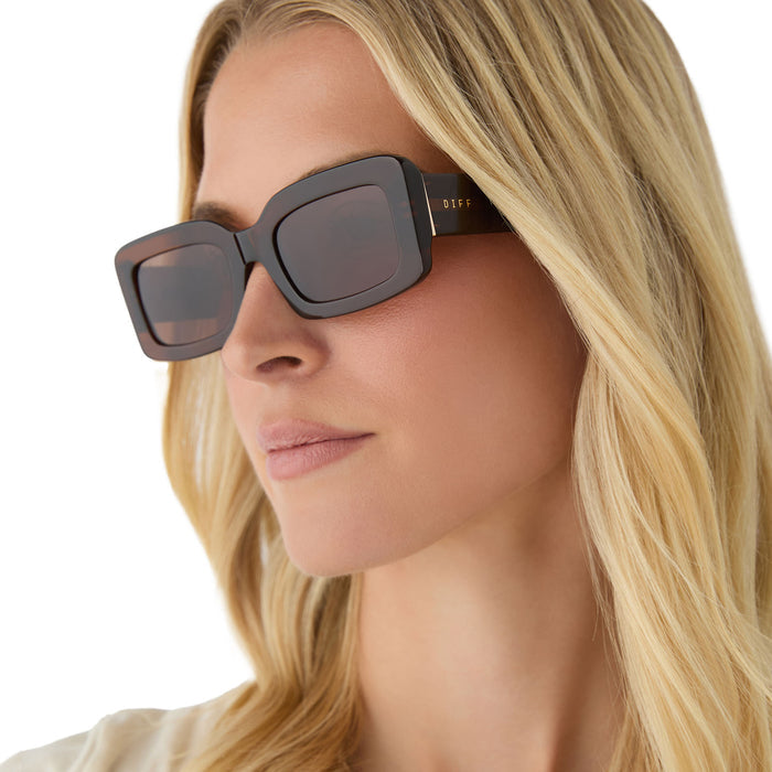 on model - female wearing diff eyewear featuring the indy rectangular sunglasses with a whiskey brown frame and brown polarized lenses angled view