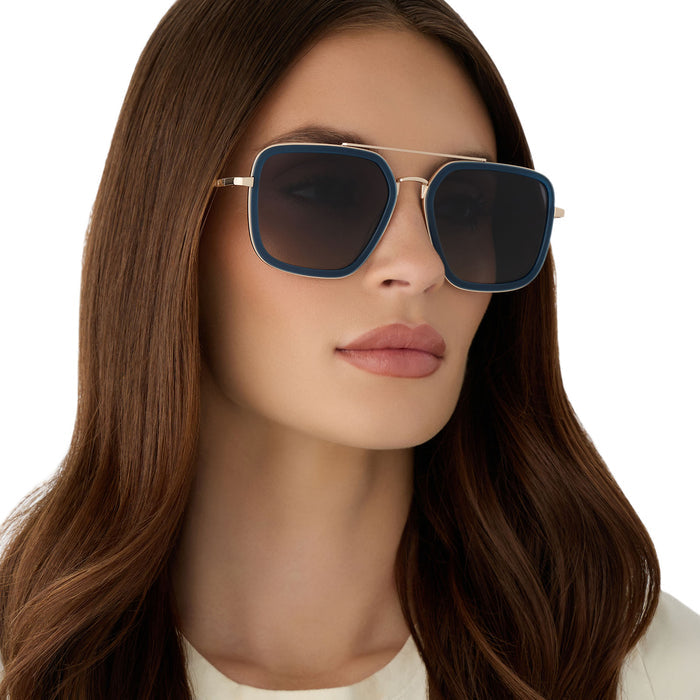 on model - female wearing diff eyewear featuring the jordan navigator sunglasses with a clubhouse blue frame and gold metal with grey gradient polarized lenses angled view