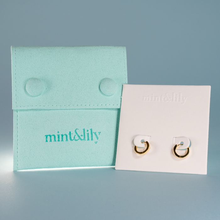 Pair of gold earrings on a white card with 'mint & lily' branding against a gray background