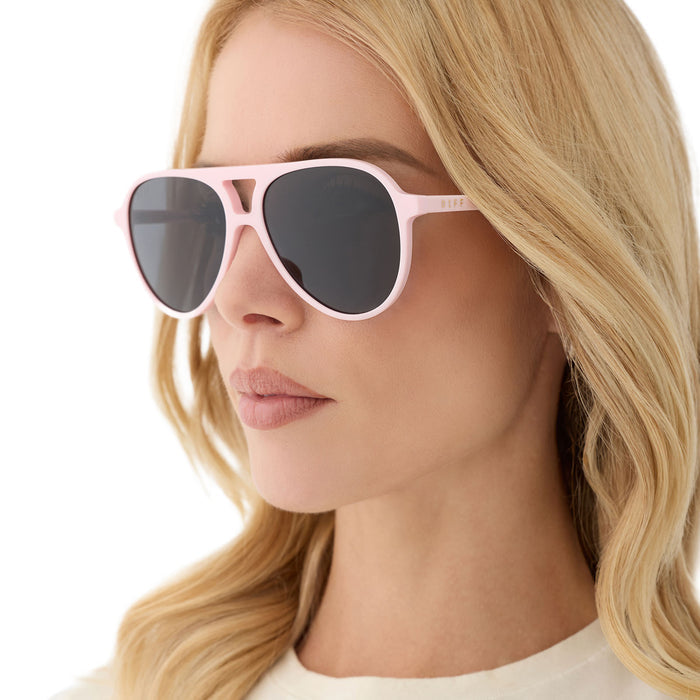 on model - female wearing diff eyewear featuring the tosca ii aviator sunglasses with a powder pink frame and grey lenses angled view