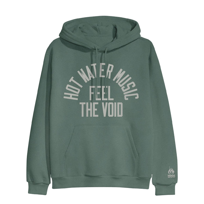 Alpine green colored pullover hoodie with HOT WATER MUSIC written across the chest in a half circle. Below that there is text that says FEEL THE VOID. On the bottom of one sleeve, there is a drawing of a fire with two lines underneath it representing water.