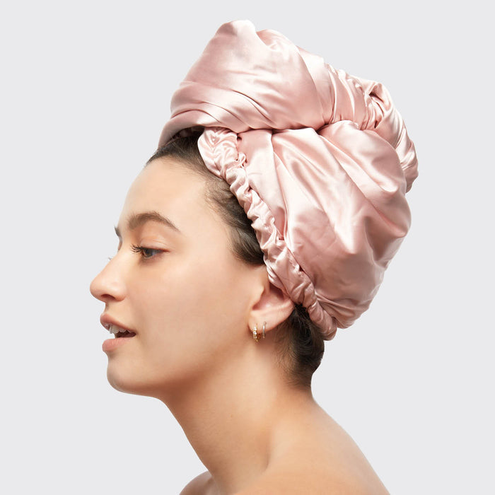 Side view of model wearing the Blush Satin Wrapped Hair Towel against a light gray background