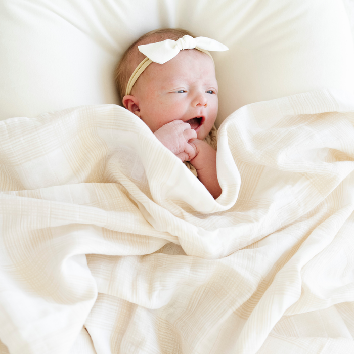 Baby girl with Perfectly Plaid Cotton Muslin Swaddle.
