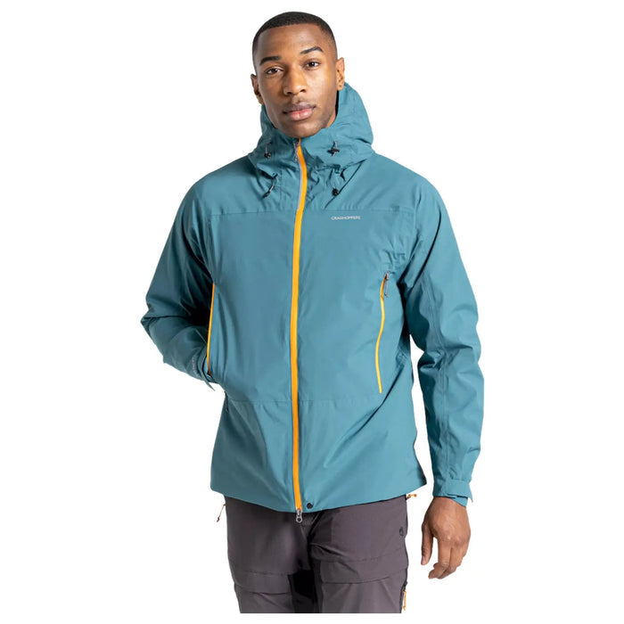 A man is wearing a teal jacket with orange accents and a hood while standing confidently in a neutral background. His expression is serious and focused.