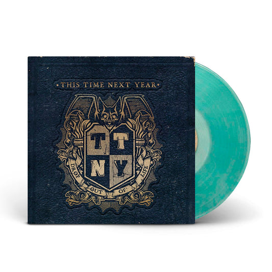 A Coke Bottle Green marbled vinyl record by This Time Next Year partially slides from a dark blue cover with a gold bat crest and the initials TTNY. The text reads “This Time Next Year” and “Drop Out Of Life.”.