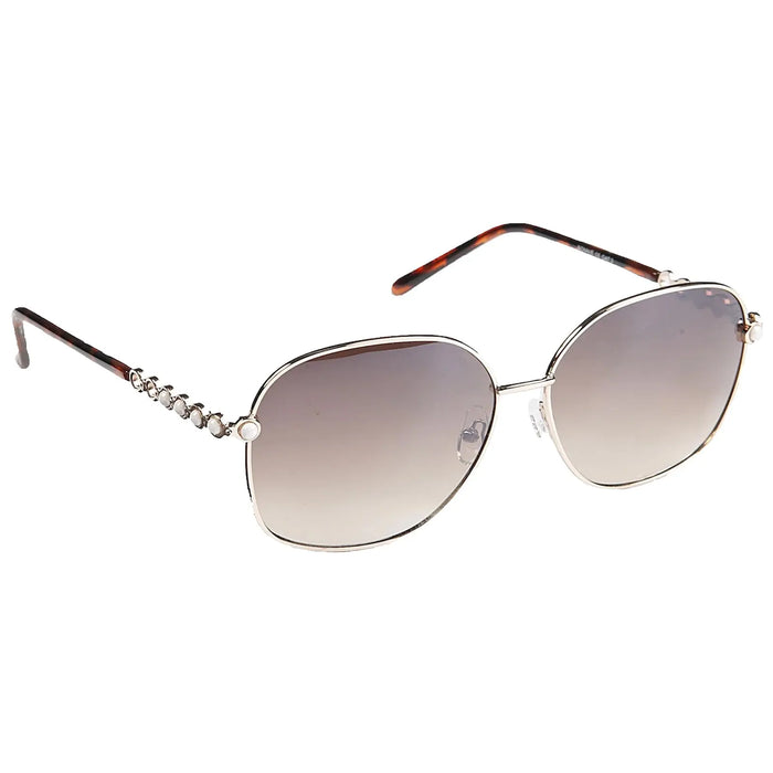 A pair of oversized sunglasses with gradient lenses is positioned on a flat surface the metallic frame features decorative stones along the arms and a tortoiseshell pattern on the tips