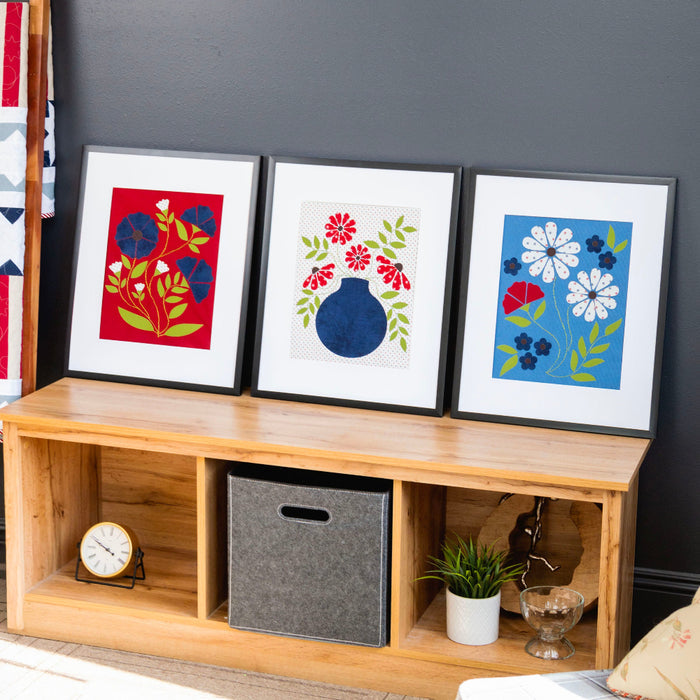Wooden shelf with decorative items and framed artworks against a dark wall.