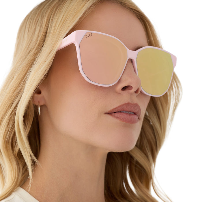 on model - female wearing diff eyewear featuring the gia square sunglasses with a powder pink frame and cherry blossom mirror lenses angled view