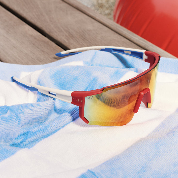 still life - diff sport featuring the heat shield sunglasses with a firecracker red frame and sunset mirror polarized lenses laying on a deck