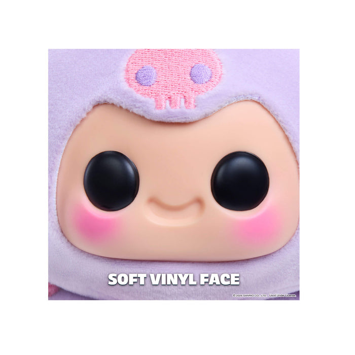 Close-up of a soft vinyl toy with a purple outfit on a white background.