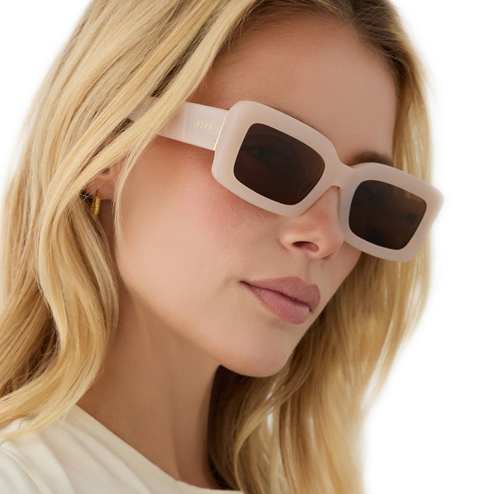 on model - female wearing diff eyewear featuring the indy rectangle sunglasses with a milky blush acetate frame and brown polarized lenses angled view