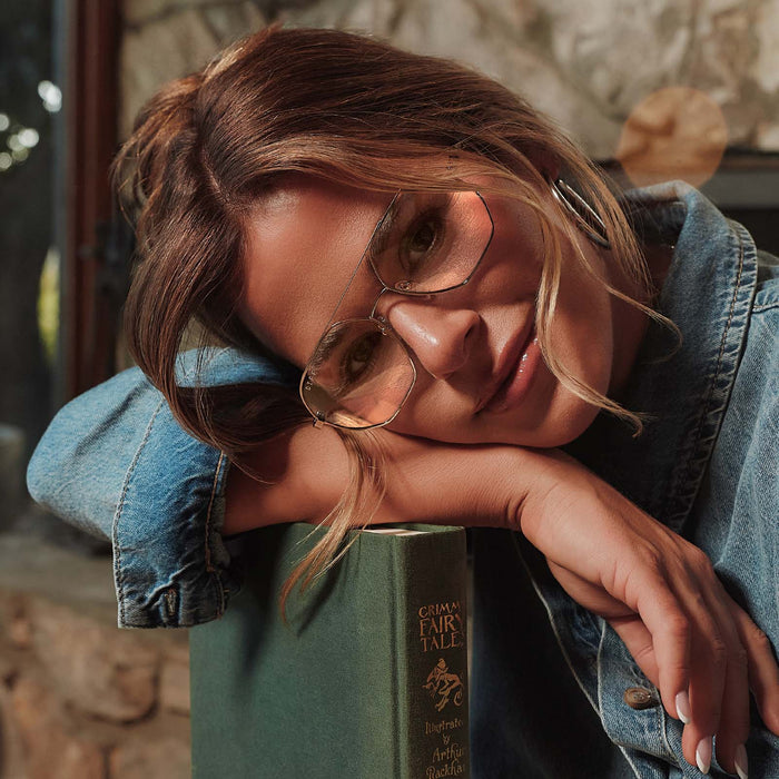 lifestyle - female jojo fletcher wearing diff eyewear joelle navigator glasses with a chocolate temple tips and gold metal frame laying on a book