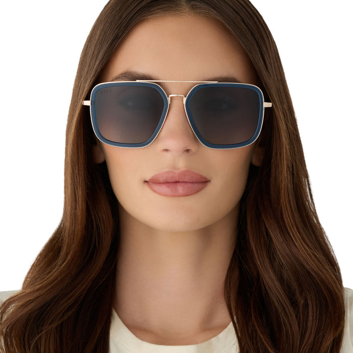 on model - female wearing diff eyewear featuring the jordan navigator sunglasses with a clubhouse blue frame and gold metal with grey gradient polarized lenses front view
