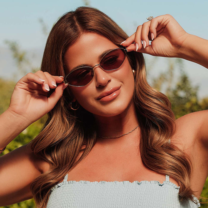 lifestyle - female jojo fletcher putting on diff eyewear jordy cat eye sunglasses with a gold metal frame with horn tortoise temples and brown lenses