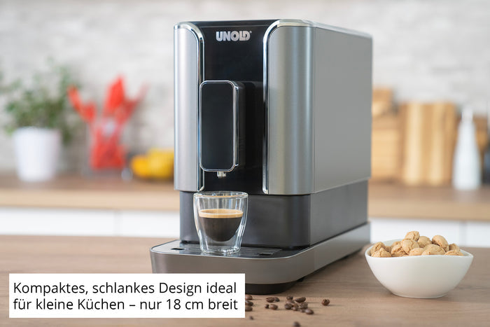 Der Unold Kaffeevollautomat LUCA, eine moderne, kompakte Espressomaschine in Silber und Schwarz, steht mit einem Glas Espresso auf der Küchentheke. Der deutsche Text unterstreicht die schlanke Breite von 18 cm – perfekt für kleine Küchen. Im Hintergrund ist eine Schale mit Nüssen zu sehen.