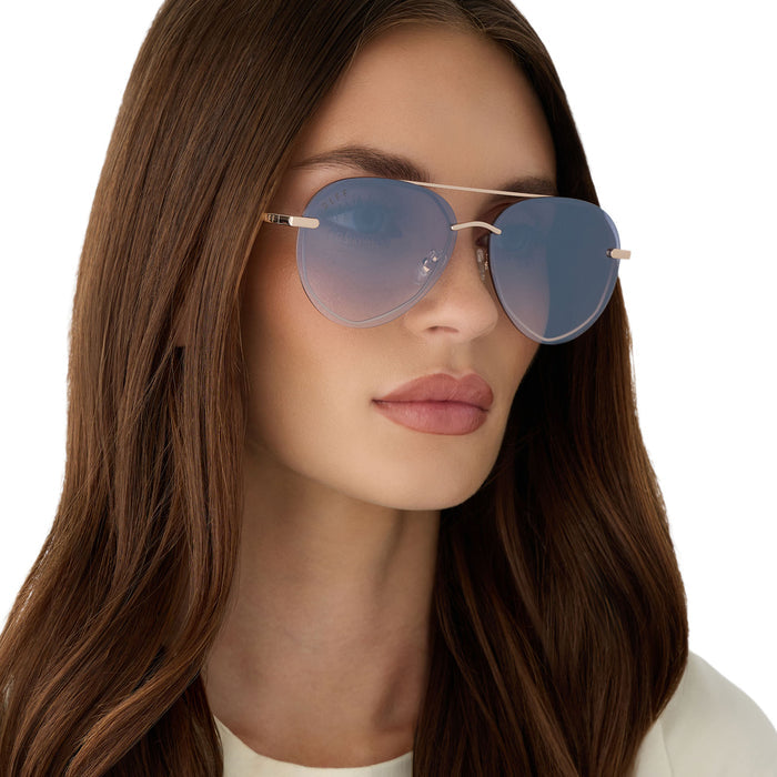 on model - female wearing diff eyewear featuring the lenox xs aviator sunglasses with a champagne gold (light gold) frame and blue slate gradient with silver flash lenses angled view