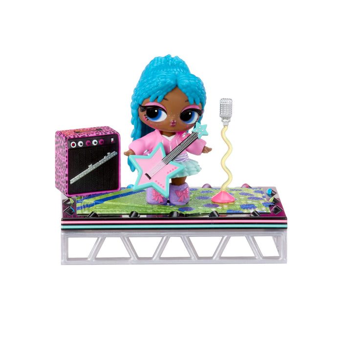 Toy doll with blue hair on a stage with guitar, amplifier, and microphone.