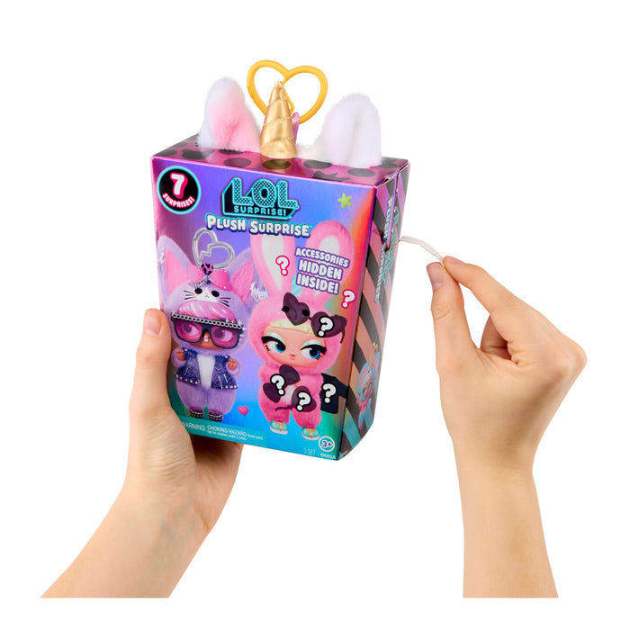 Hands holding a LOL Surprise plush toy packaging with pink ears and unicorn horn on a white background