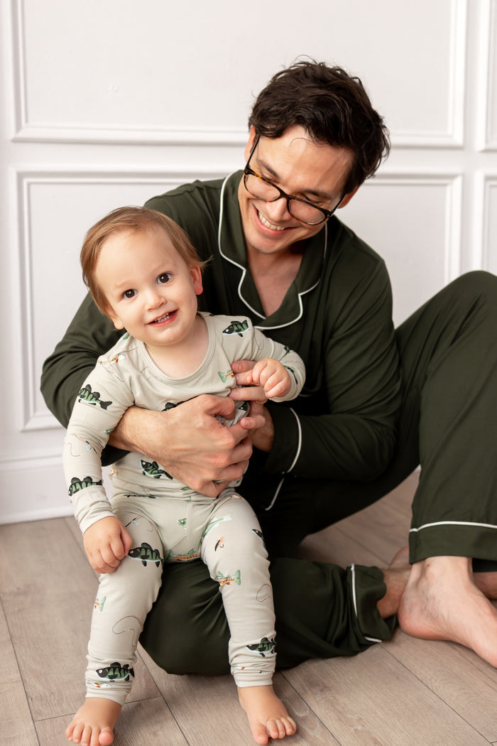 toddler in fishing printed pajamas and dad in dark green coordinating pajamas