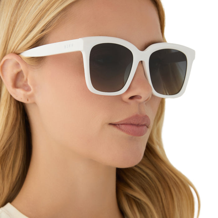 on model - blonde female wearing diff eyewear featuring the meredith square oversized sunglasses with a white snowbound acetate frame and grey gradient polarized lenses angled view