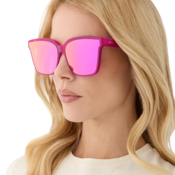 on model - blonde female wearing diff eyewear featuring the meredith ii square sunglasses with a bright pink tulip frame and pink mirror lenses angled view