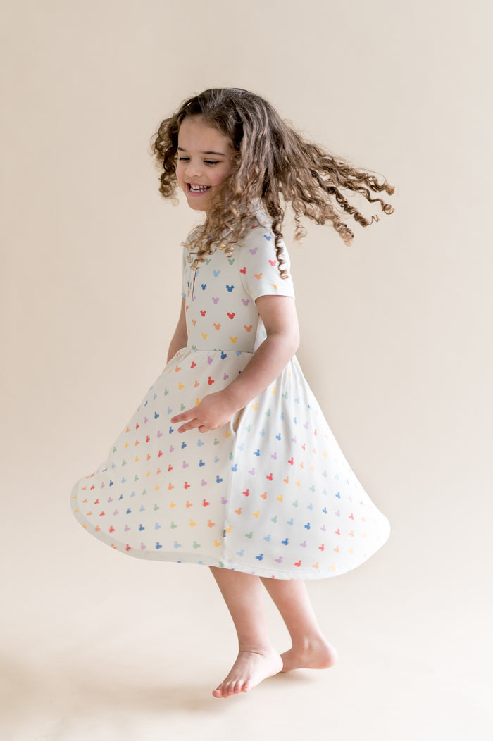 Young girl in a cream dress with colorful mickey heads on a beige background