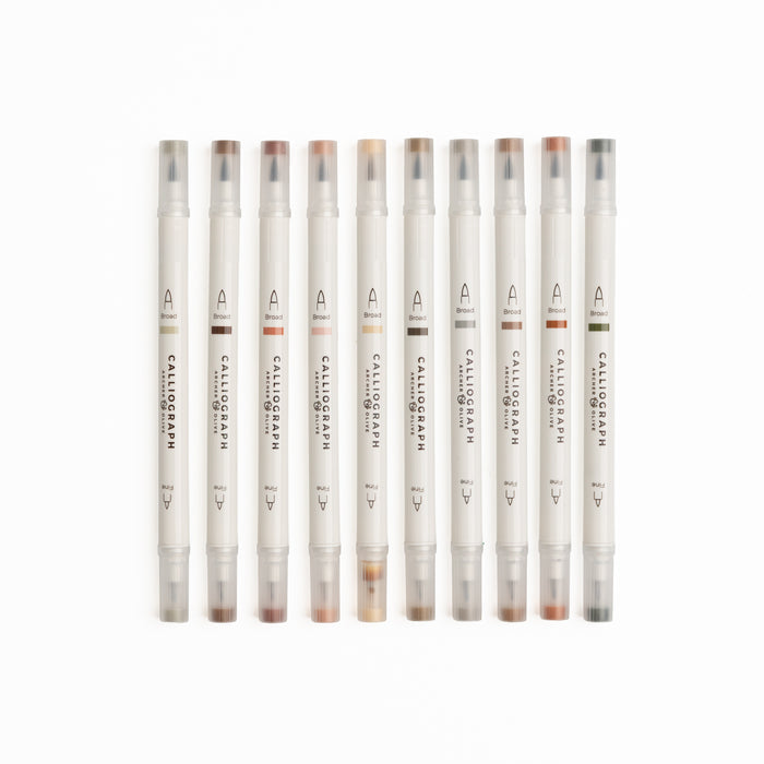 Set of ten Quiet Corners calligraphy pens with flexible brush tips laid out with lettering samples