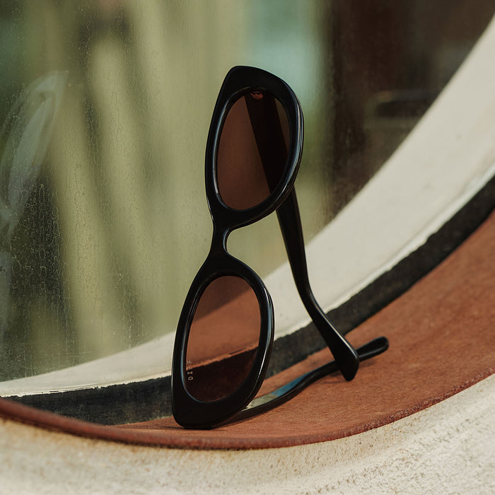 still life - jojo fletcher x diff eyewear jordy round cat eye sunglasses with a black acetate frame and brown lenses