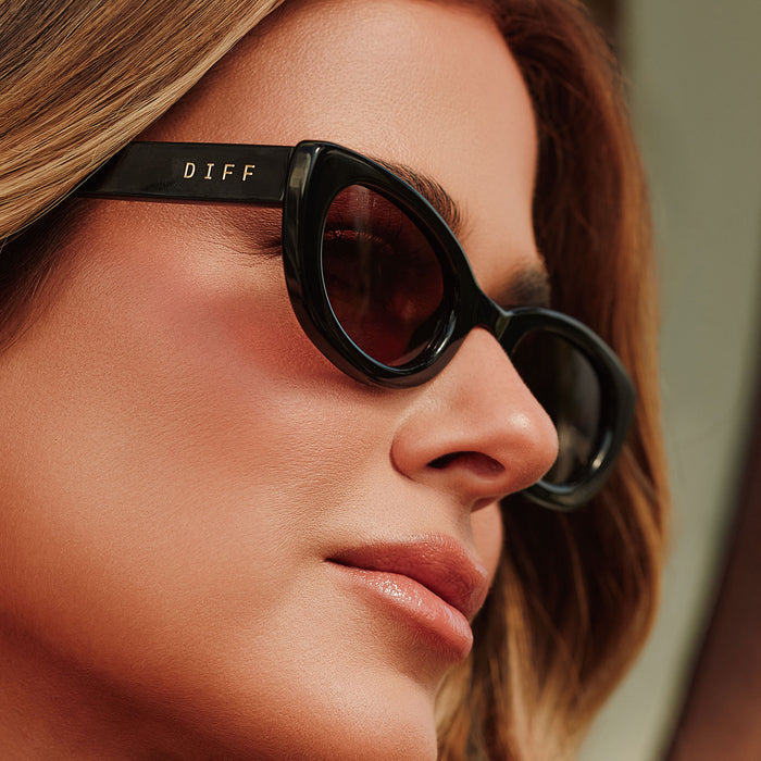 lifestyle - female jojo fletcher wearing diff eyewear jordy round cat eye sunglasses with a black acetate frame and brown lenses detailed view