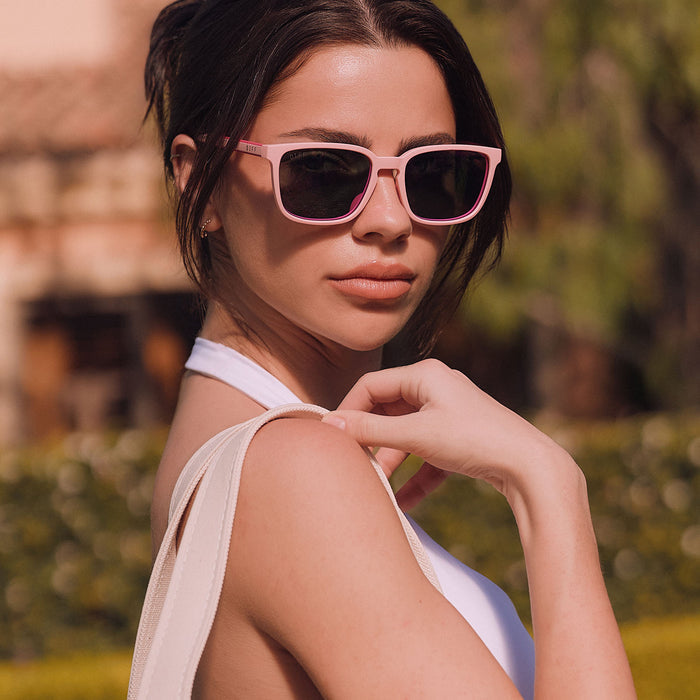 lifestyle - female at a country club wearing diff sport featuring the rush square sunglasses with a matte baby pink frame and pink rush mirror polarized lenses