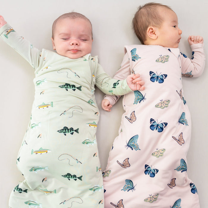 Two infants wearing 1.0 Sleep Bags in  Fishing and Blush Butterfly