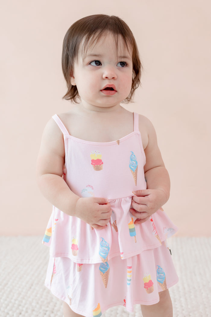 Child wearing spaghetti strap ruffle romper in Sakura Ice Cream print on a beige background