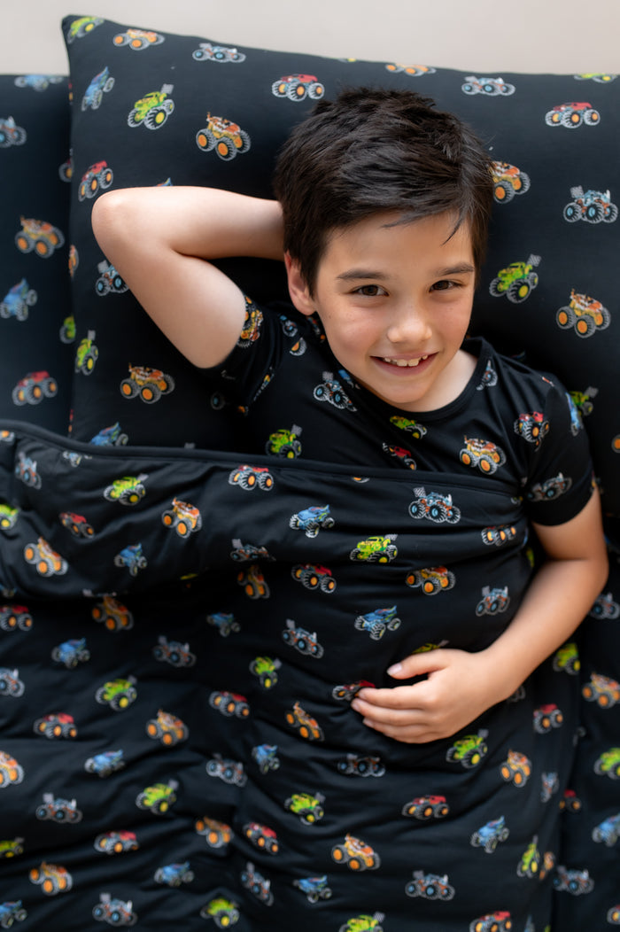 Boy lying on black Standard Pillowcase and sheet in Monster Truck print covered with similar print  Blanket