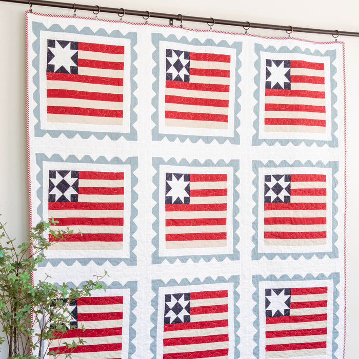 Quilt with American flag pattern hanging on a wall in a room.