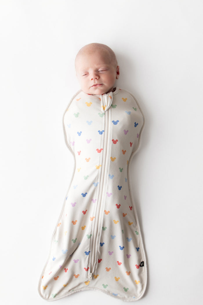 Baby asleep in kyte baby swaddle bag with pastel mickey head pattern