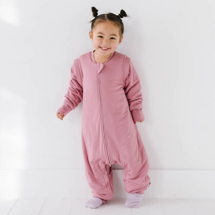 A toddler wearing a pink seed suit with long sleeves, designed for warmth and comfort.