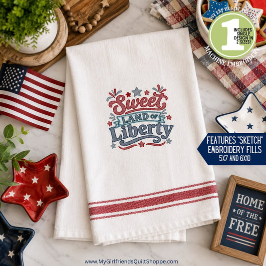Embroidered towel with 'Sweet Land of Liberty' design on a table with patriotic decor.