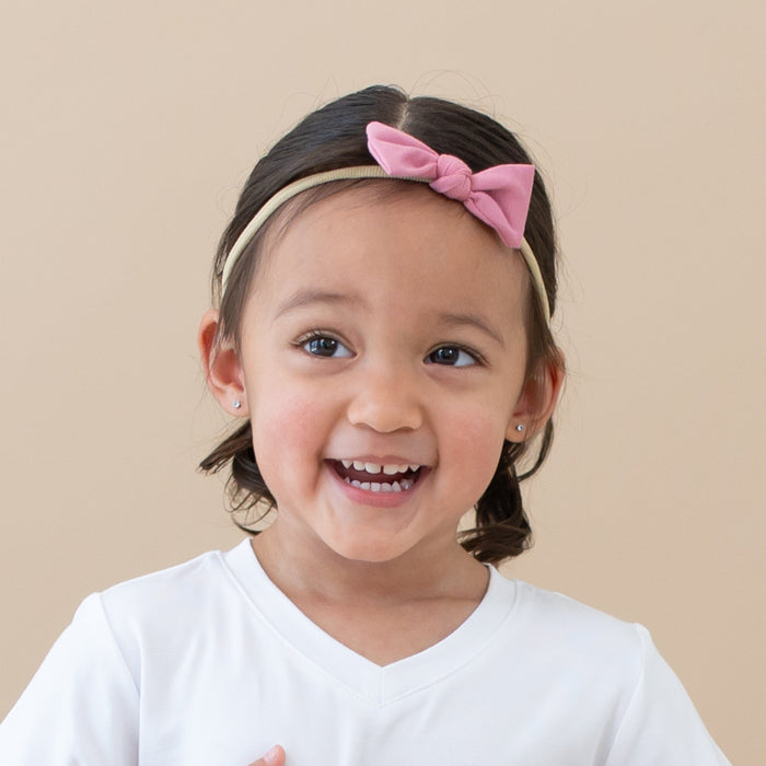Toddler wearing Kyte Baby Tiny Nylon Bow in Apple Blossom