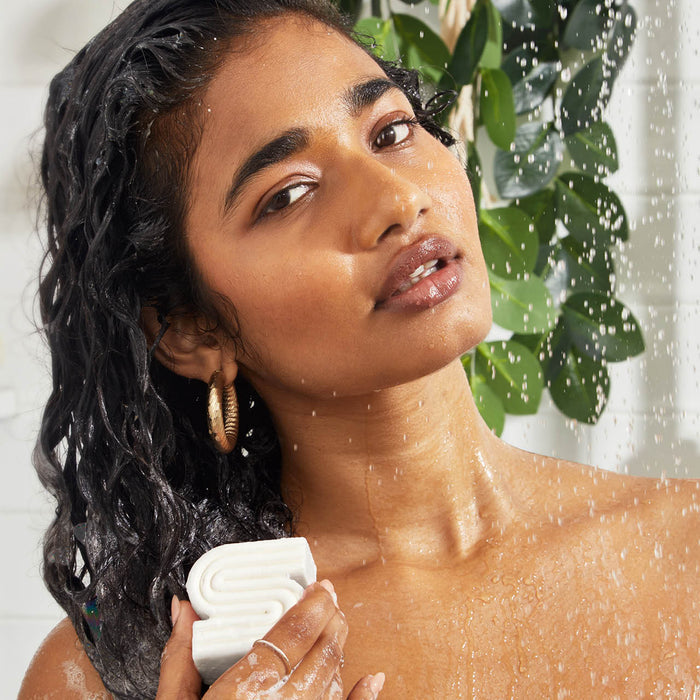 woman using a sudsy ultra sensitive solid shampoo bar on her hair