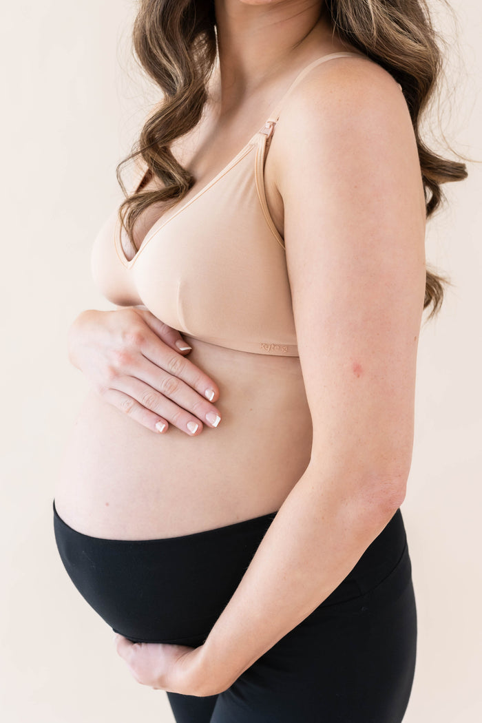 Pregnant woman wearing beige Nursing Bra with black leggings