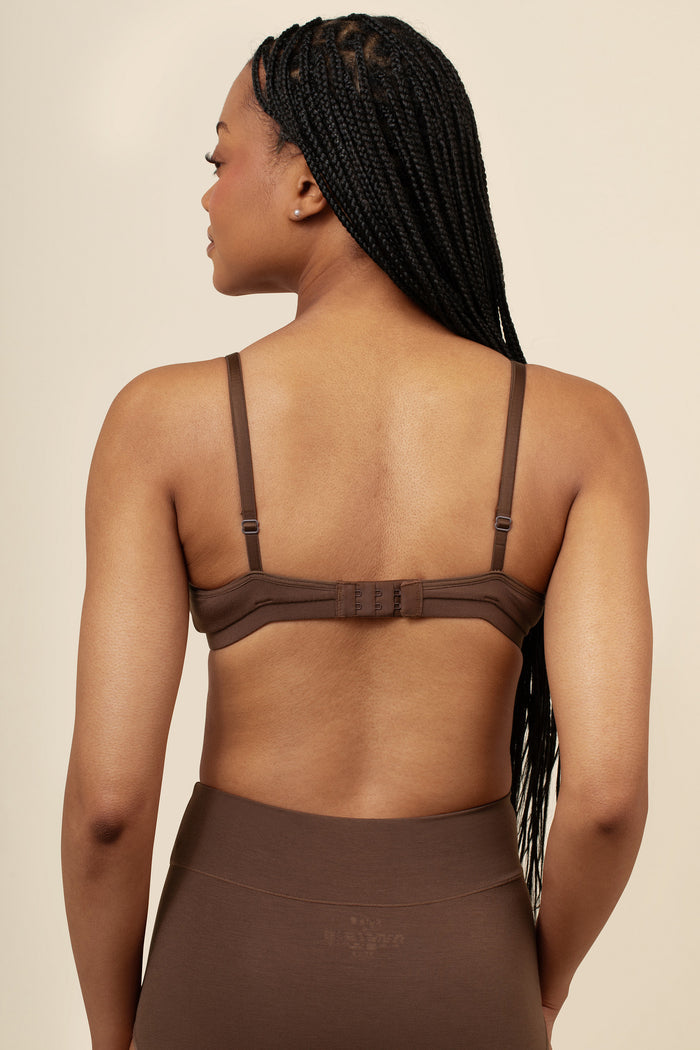 Woman wearing a brown bra and pants against a beige background