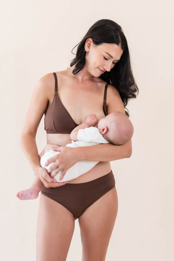 Female model nursing her infant wearing the Women's Nursing Bra in Latte