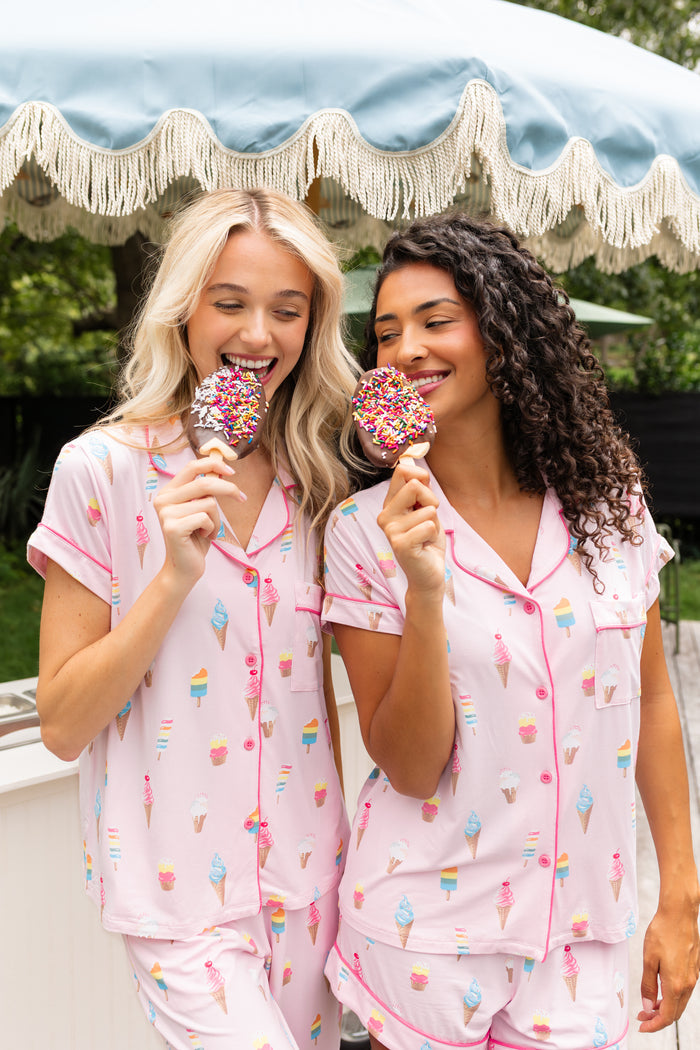 Two Models wearing Women's Short Sleeve Pajama Set and Women's Short Sleeve Cropped Pajama Set in Sakura Ice Cream print outdoors with an ice cream stick
