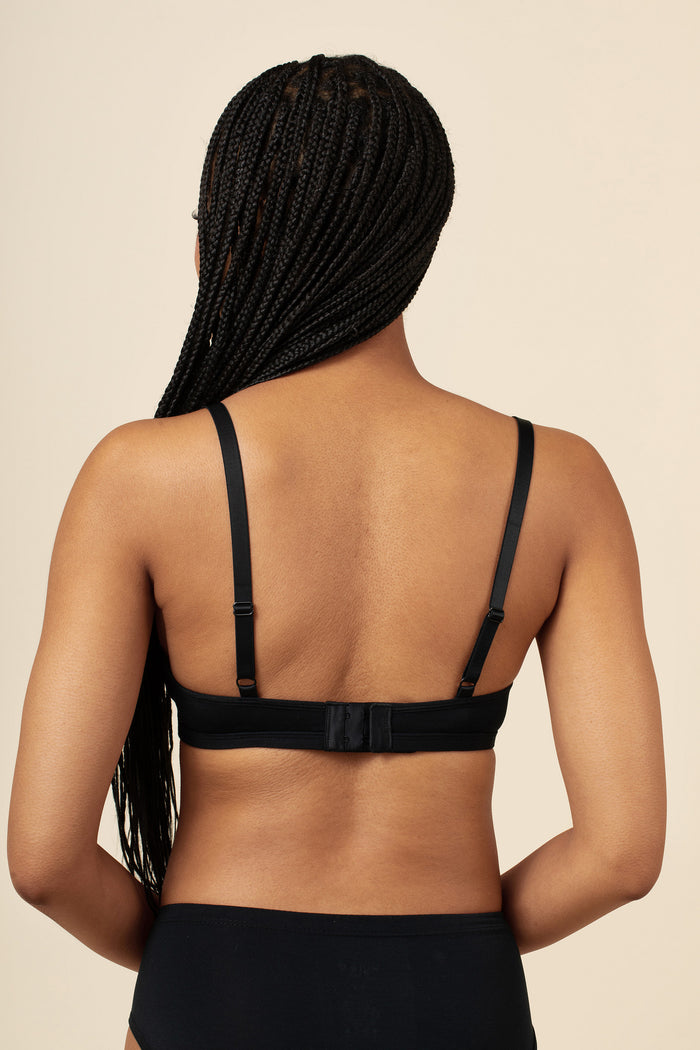 Person wearing a black bralette on a beige background