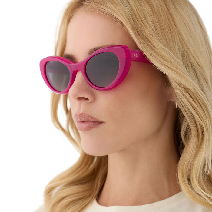 on model - female wearing diff eyewear featuring the zaria cat eye sunglasses with a bright tulip pink frame and grey gradient polarized lenses angled view